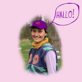 Ein Foto von Lina. Sie lächelt, hat eine Cappi auf und steht im Grünen. In einer Sprechblase steht: Hallo!